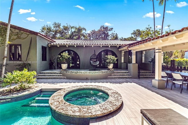 rear view of property featuring a swimming pool with hot tub