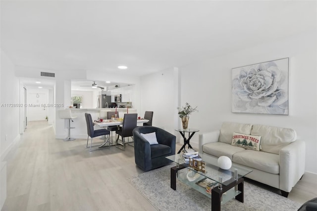 living room featuring ceiling fan and light hardwood / wood-style flooring