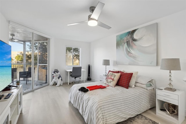 bedroom featuring light wood-type flooring, ceiling fan, expansive windows, and access to outside