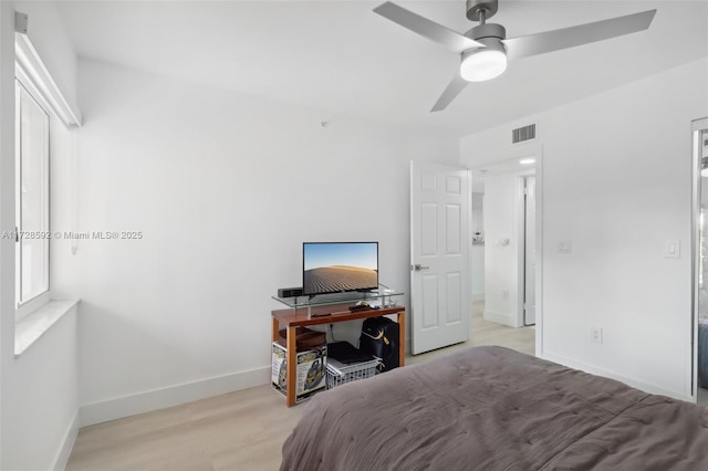 bedroom featuring ceiling fan, multiple windows, and light hardwood / wood-style flooring