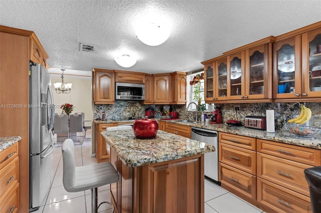 kitchen featuring tasteful backsplash, a notable chandelier, a kitchen island, appliances with stainless steel finishes, and light tile patterned floors