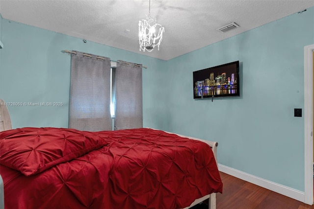 bedroom featuring hardwood / wood-style floors, a textured ceiling, and an inviting chandelier