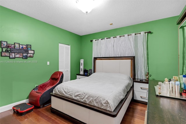 bedroom featuring a closet, dark wood-type flooring, and a textured ceiling