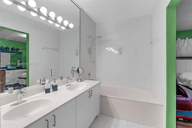 bathroom with a textured ceiling, tile patterned flooring, tiled shower / bath, and vanity