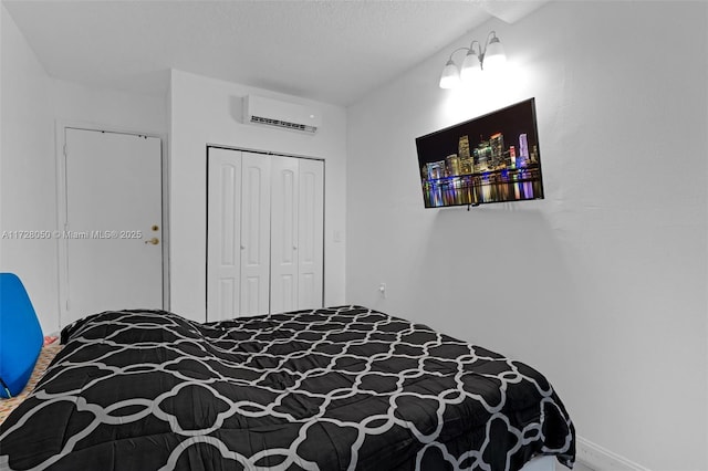 bedroom featuring a closet, a textured ceiling, and a wall unit AC