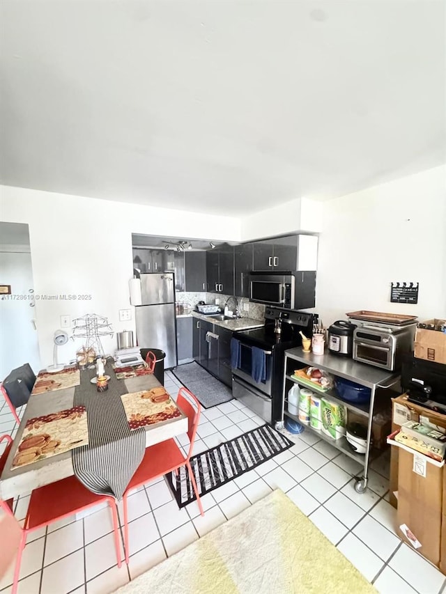 kitchen with light tile patterned floors, backsplash, sink, and stainless steel appliances