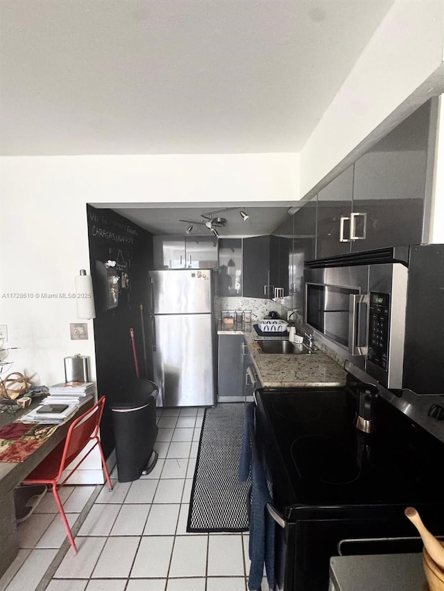 kitchen with light tile patterned floors, stainless steel appliances, stone countertops, and sink