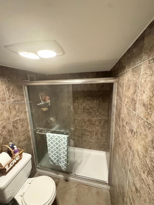 bathroom featuring walk in shower, tile walls, and toilet