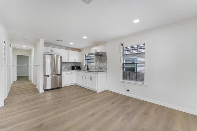kitchen with light countertops, ornamental molding, a sink, stainless steel appliances, and light wood-type flooring