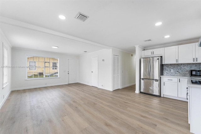 kitchen with light wood-type flooring, ornamental molding, stainless steel fridge, white cabinets, and backsplash