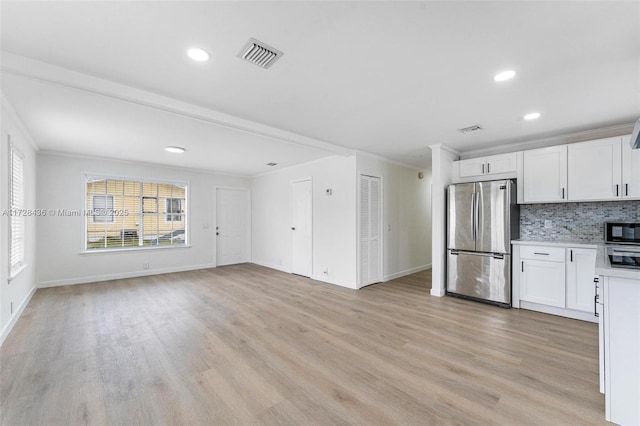 kitchen with freestanding refrigerator, crown molding, visible vents, and light wood finished floors
