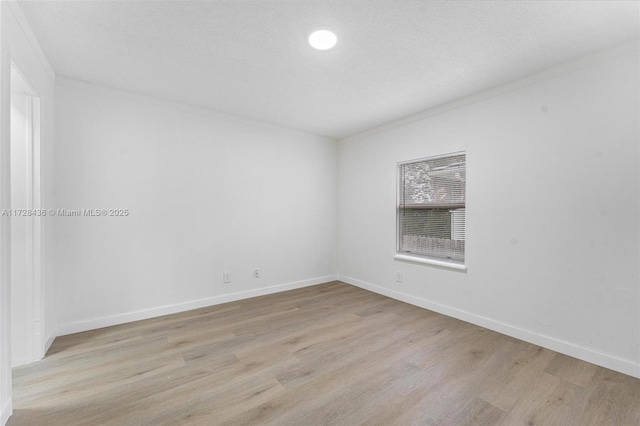 spare room featuring crown molding, light hardwood / wood-style floors, and a textured ceiling