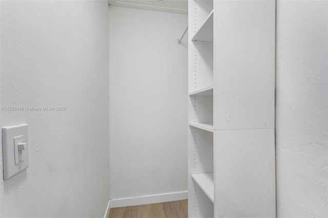 walk in closet with light wood-style floors