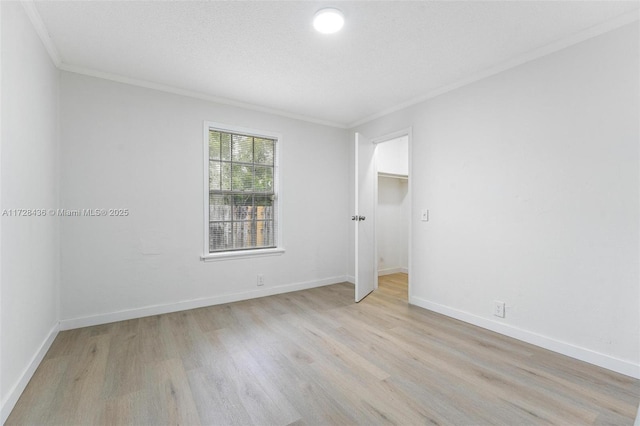 spare room featuring ornamental molding, a textured ceiling, and light hardwood / wood-style floors