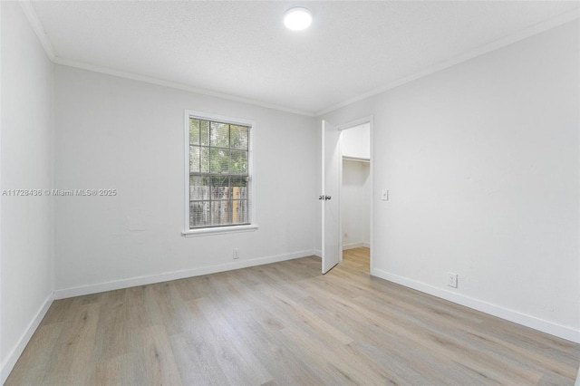 unfurnished bedroom with crown molding, light wood-type flooring, and baseboards