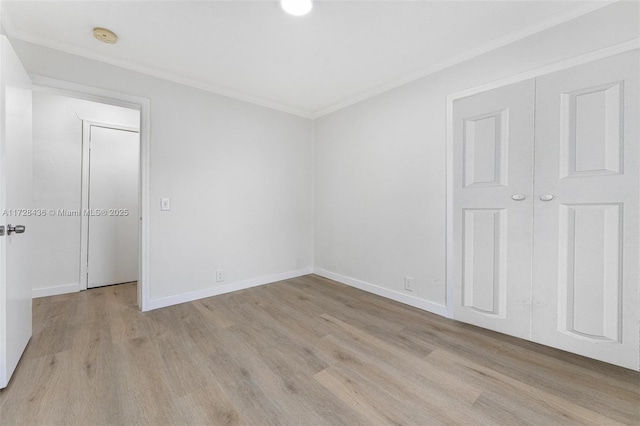 unfurnished bedroom with crown molding, light wood-style flooring, baseboards, and a closet