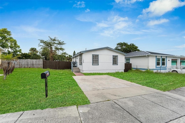 view of front of property featuring concrete driveway, stucco siding, a front lawn, and fence
