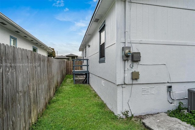 view of side of home with a yard, central air condition unit, fence, and crawl space