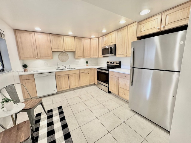 kitchen featuring light tile patterned floors, light brown cabinetry, appliances with stainless steel finishes, and sink