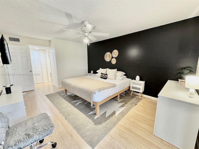 bedroom featuring a textured ceiling, ceiling fan, and light hardwood / wood-style floors