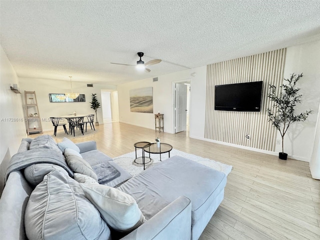 living room with ceiling fan, light hardwood / wood-style floors, and a textured ceiling