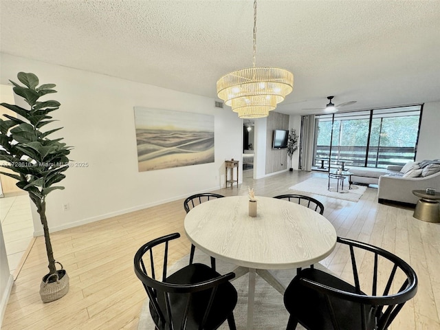 dining area featuring ceiling fan with notable chandelier, light hardwood / wood-style floors, a textured ceiling, and floor to ceiling windows