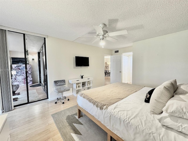 bedroom with ceiling fan, access to exterior, light hardwood / wood-style floors, expansive windows, and a textured ceiling