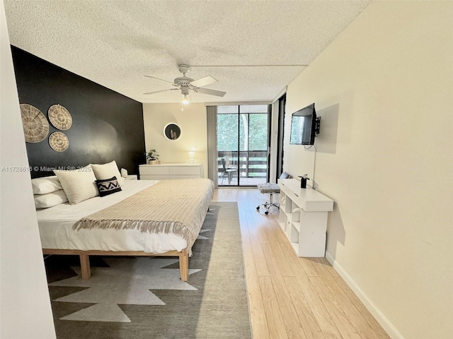 bedroom featuring ceiling fan, access to outside, light wood-type flooring, a textured ceiling, and a wall of windows