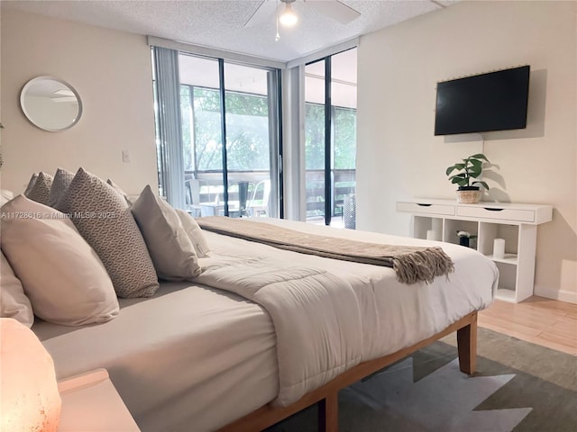 bedroom with ceiling fan, expansive windows, access to exterior, and a textured ceiling