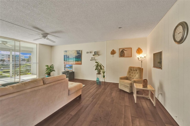 living room with ceiling fan, a textured ceiling, dark hardwood / wood-style floors, and wooden walls