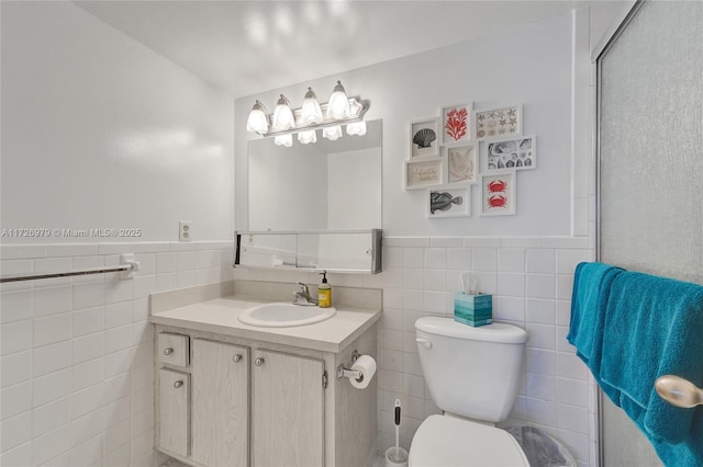 bathroom with toilet, vanity, and tile walls