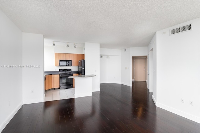 kitchen with light hardwood / wood-style floors, a textured ceiling, black appliances, and track lighting