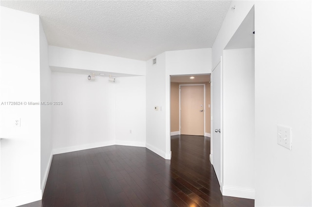 unfurnished room with a textured ceiling and dark hardwood / wood-style floors