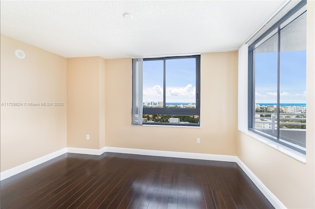 unfurnished room featuring dark hardwood / wood-style flooring and a textured ceiling