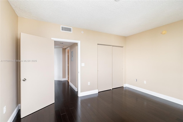 unfurnished bedroom featuring a closet, dark hardwood / wood-style flooring, and a textured ceiling