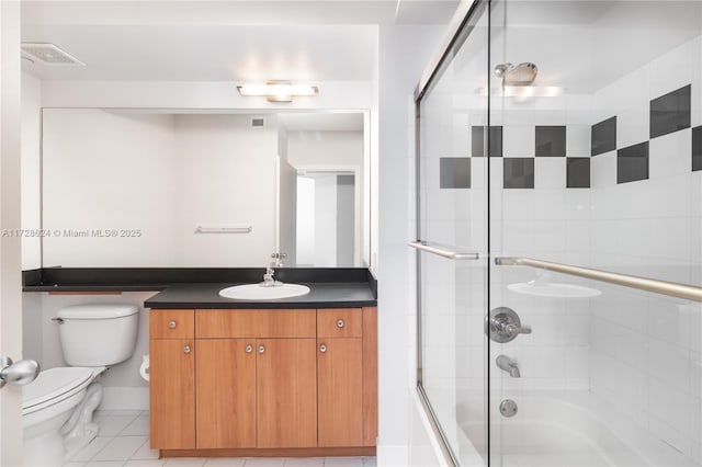 full bathroom with tile patterned floors, bath / shower combo with glass door, toilet, and vanity