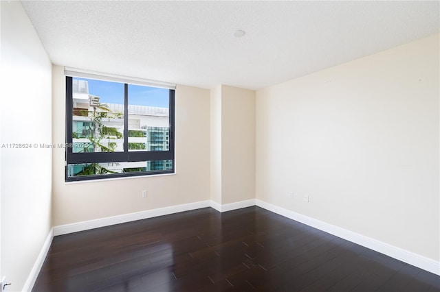 empty room featuring a textured ceiling and dark hardwood / wood-style flooring