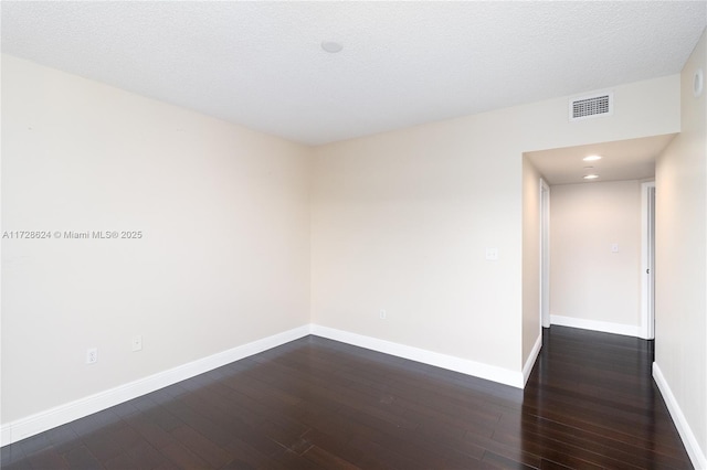 unfurnished room with a textured ceiling and dark hardwood / wood-style floors