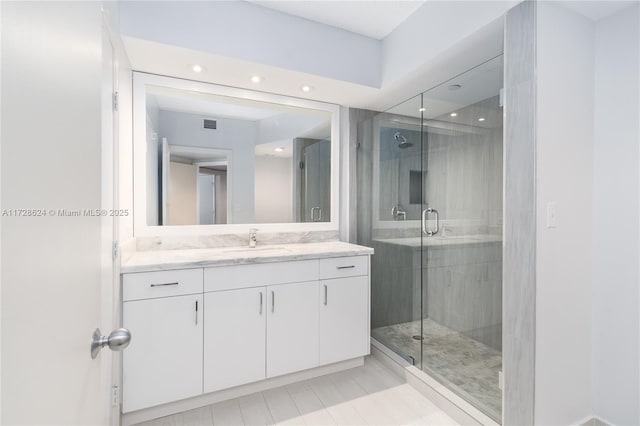 bathroom with an enclosed shower, vanity, and tile patterned flooring