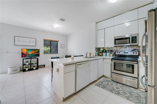 kitchen with white cabinets, kitchen peninsula, appliances with stainless steel finishes, and light tile patterned floors