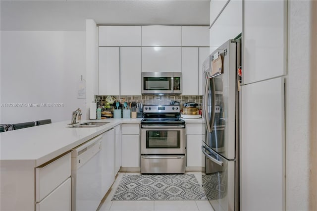 kitchen with white cabinets, kitchen peninsula, appliances with stainless steel finishes, and sink