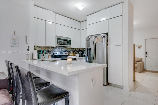 kitchen with sink, white cabinetry, a kitchen breakfast bar, a textured ceiling, and stainless steel appliances