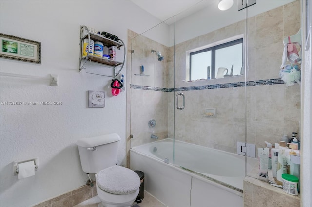 bathroom featuring combined bath / shower with glass door and toilet