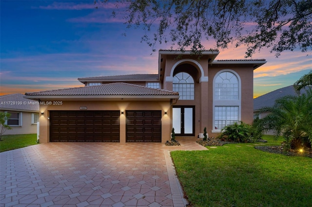 mediterranean / spanish house featuring a garage and a lawn