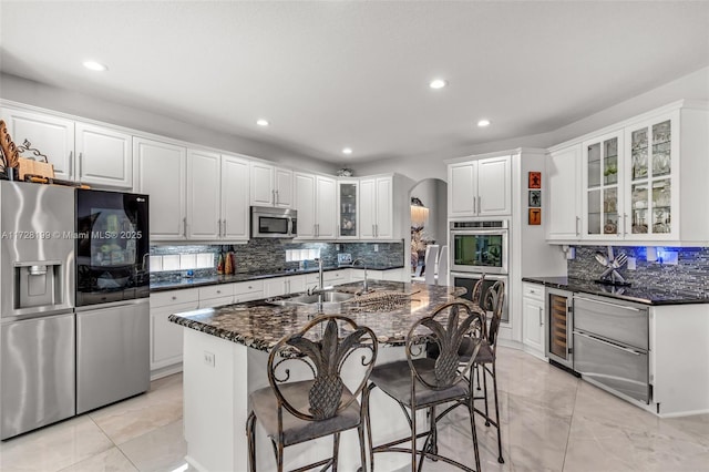 kitchen with an island with sink, appliances with stainless steel finishes, sink, and white cabinets