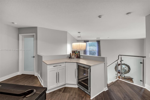 kitchen featuring pendant lighting, white cabinetry, wine cooler, dark wood-type flooring, and a textured ceiling