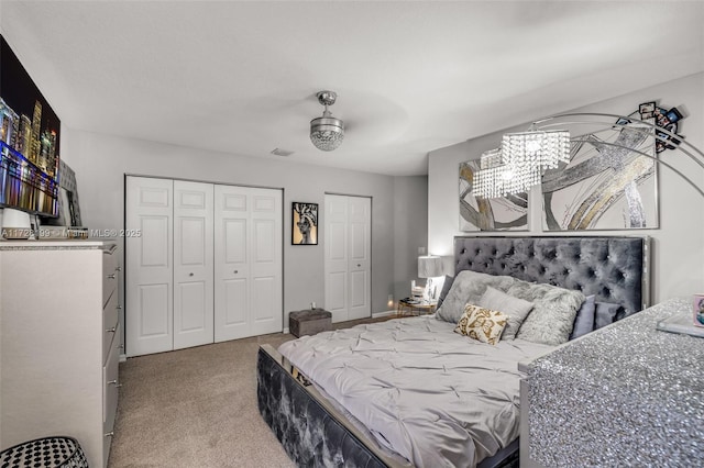 carpeted bedroom with ceiling fan and two closets