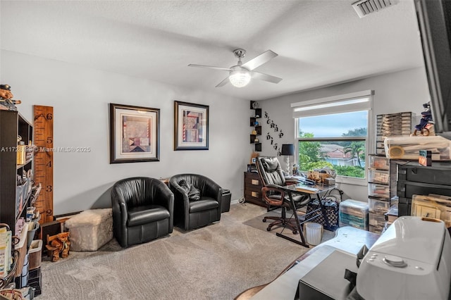 carpeted home office with ceiling fan and a textured ceiling