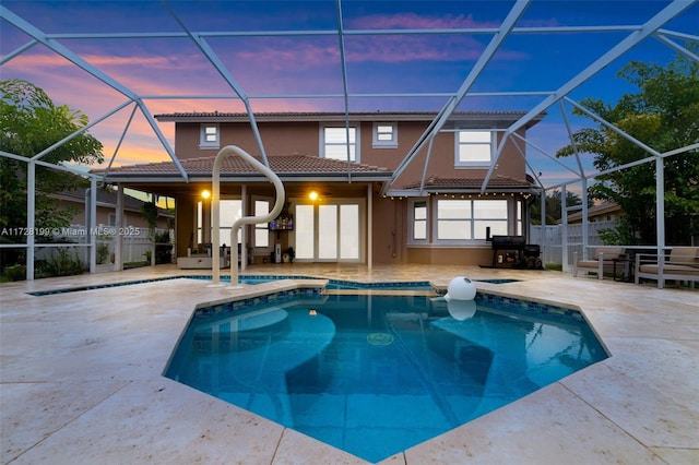 pool at dusk featuring a patio and a lanai