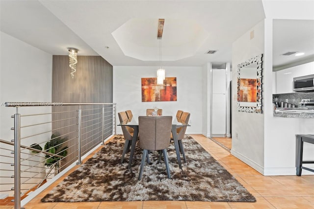 dining room with a raised ceiling and light tile patterned flooring